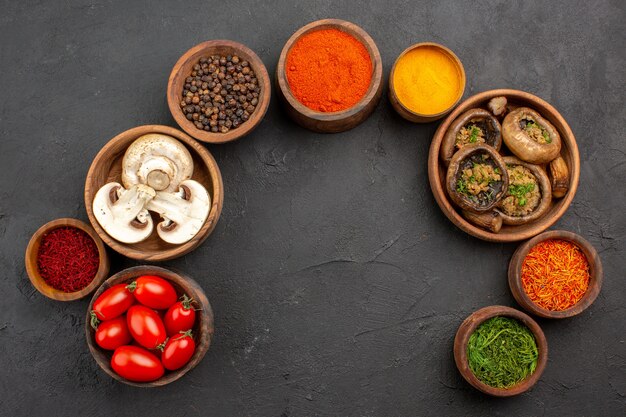 Draufsicht gebratene Pilze mit Tomaten und Gewürzen auf dunklem Hintergrund