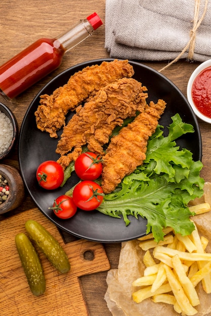 Draufsicht gebratenes Huhn mit Tomaten und Salat auf Teller mit Pommes