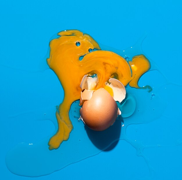 Draufsicht gebrochenes Ei auf blauem Hintergrund
