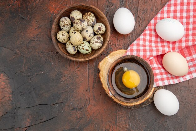 Draufsicht gebrochenes rohes Ei innerhalb des Tellers mit Hühner- und Wachteleiern
