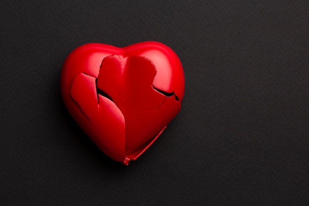 Draufsicht gebrochenes rotes Herz auf dunklem Hintergrund