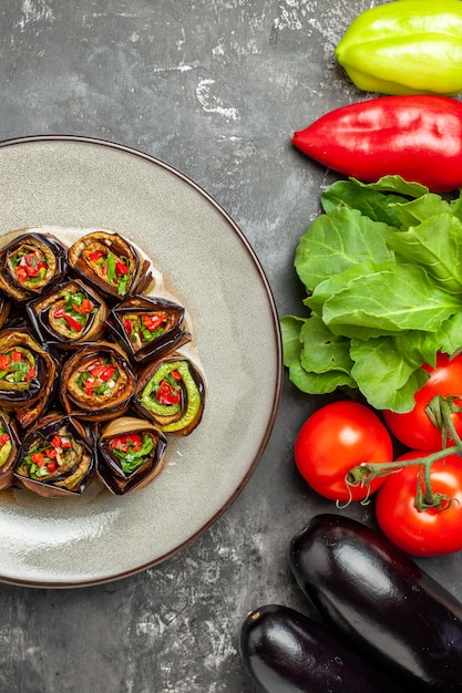 Kostenloses Foto draufsicht gefüllte auberginenröllchen in weißen teller tomaten paprika auberginen auf grauem hintergrund