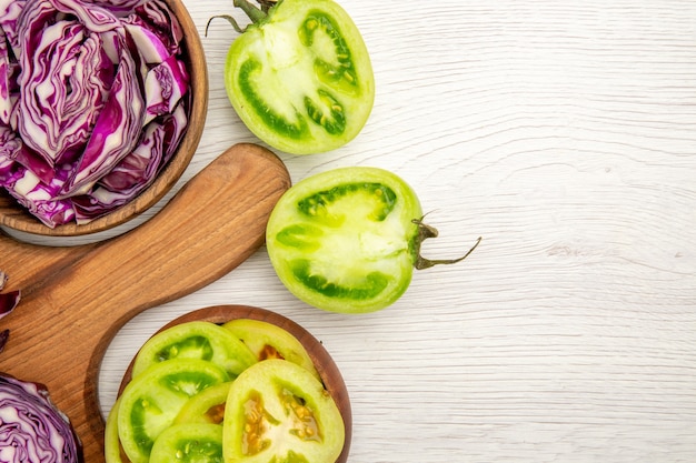 Draufsicht gehackter Rotkohl in Schüssel geschnittenen grünen Tomaten in Schüssel auf weißem Tisch freien Raum