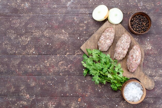 Draufsicht gehacktes rohes Fleischkotelett gebildet mit grünem Zwiebelsalz auf dem braunen Schreibtischfleisch-Rohkostmehlgrün