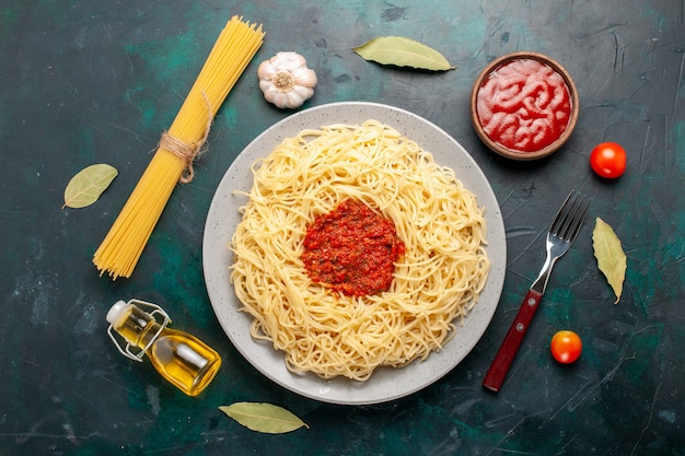 Draufsicht gekochte italienische Nudeln mit gehacktem Tomatenfleisch auf dem dunkelblauen Schreibtisch