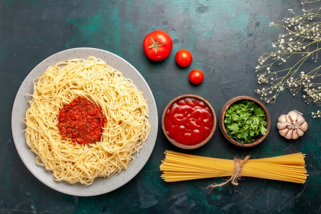 Draufsicht gekochte italienische Nudeln mit Hackfleisch-Tomatensauce und Gewürzen auf dunkelblauer Oberfläche