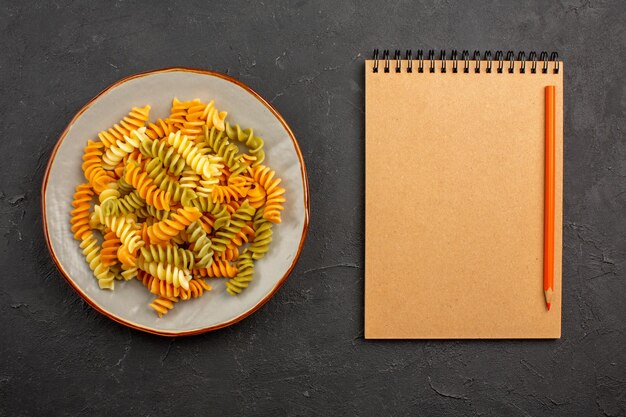 Draufsicht gekochte italienische Pasta ungewöhnliche Spiralnudeln im Teller auf dem dunklen Raum