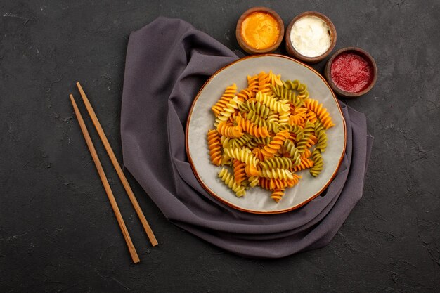 Draufsicht gekochte italienische Pasta ungewöhnliche Spiralnudeln mit Gewürzen auf dem dunklen Raum