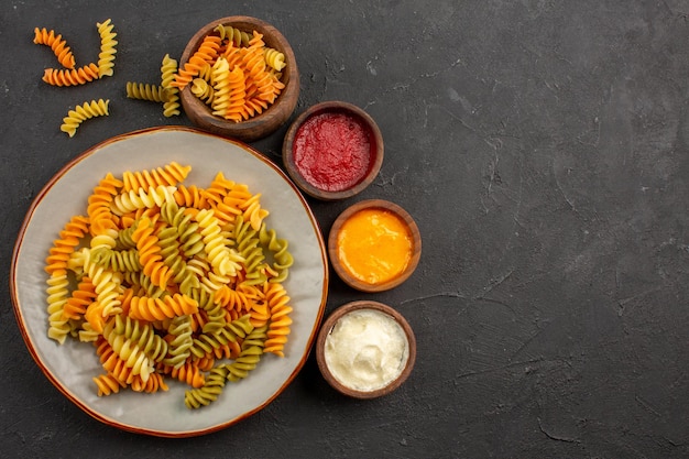 Draufsicht gekochte italienische Pasta ungewöhnliche Spiralnudeln mit Gewürzen auf dem dunklen Raum