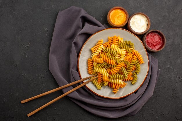 Draufsicht gekochte italienische Pasta ungewöhnliche Spiralnudeln mit Gewürzen auf dem dunklen Raum