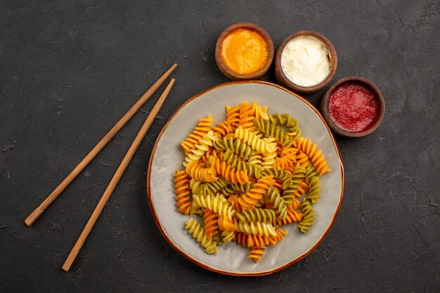 Draufsicht gekochte italienische Pasta ungewöhnliche Spiralnudeln mit Gewürzen auf dem dunklen Raum