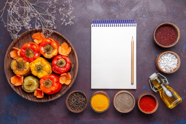 Draufsicht gekochte Paprika mit Hackfleisch und verschiedenen Gewürzen auf dunklem Schreibtischfleisch Gemüse Rindfleisch Mahlzeit Essen