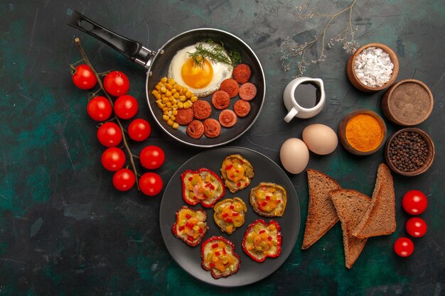 Draufsicht gekochte Paprika mit Rühreibrot und Würstchen auf der dunkelgrünen Oberfläche