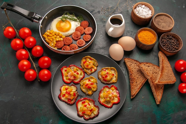 Draufsicht gekochte Paprika mit Rühreigewürzen und Würstchen auf der dunkelgrünen Oberfläche