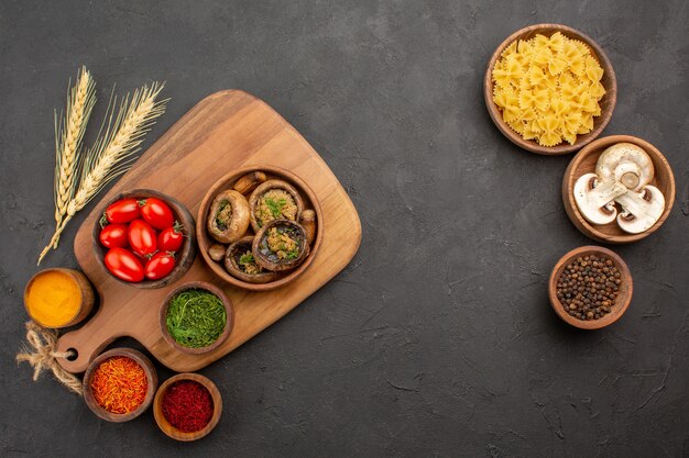 Draufsicht gekochte Pilze mit Gewürzen auf dunklen Tafel reifen Speckpilzen