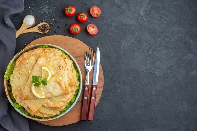 Draufsicht gekochte Pita Innenplatte mit Gemüse und Zitronenscheiben auf dunkler Oberfläche