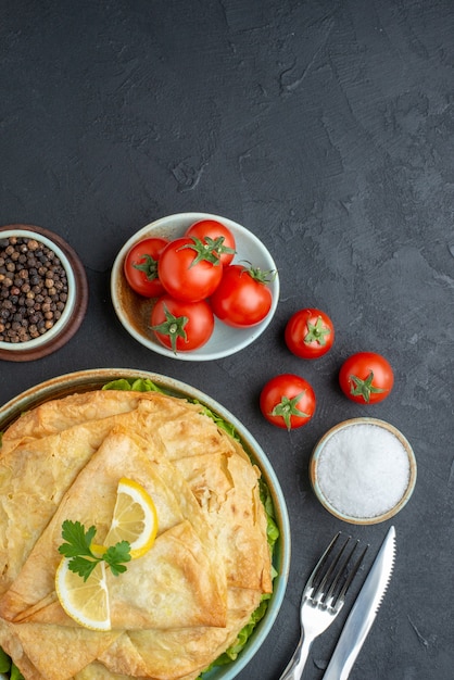 Kostenloses Foto draufsicht gekochte pita innenplatte mit zitronenscheiben und tomaten auf dunkler oberfläche