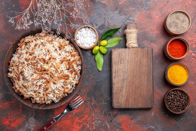 Draufsicht gekochter Reis mit Gewürzen auf der dunklen Oberfläche dunkles Mahlzeitfotoschalenfutter