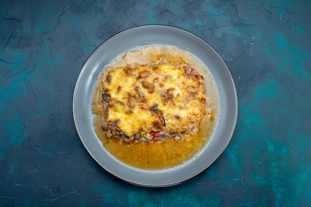 Draufsicht gekochtes fleischgericht mit soße und pilzen innerhalb platte auf dem dunkelblauen schreibtisch fleischgericht abendessen essen mahlzeit