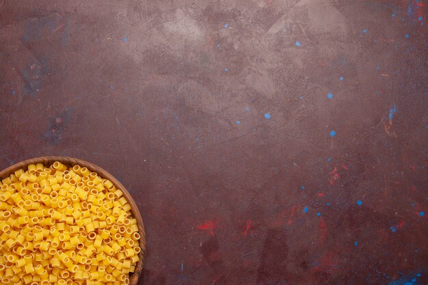 Draufsicht gelbe italienische Nudeln roh wenig gebildet auf dem dunkelvioletten Hintergrund Nudelnahrungsmittel rohen Mahlzeit Teig