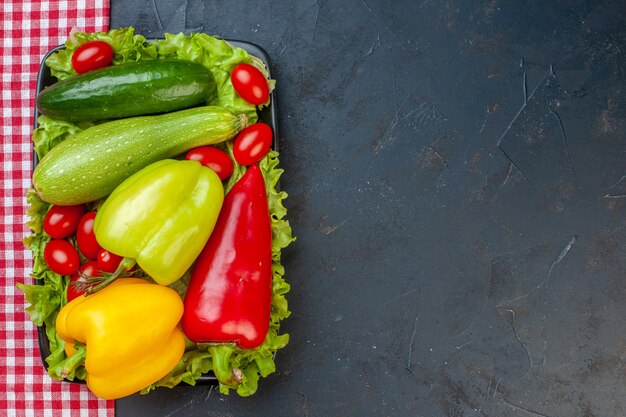 Draufsicht Gemüse bunte Paprika Zucchini Kirschtomaten Salat Gurke auf schwarzem rechteckigem Teller