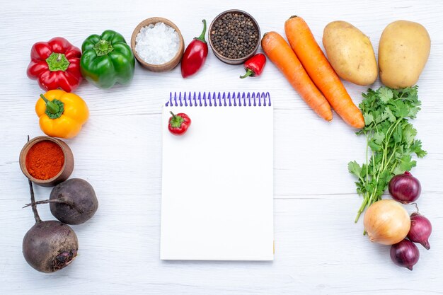 Draufsicht Gemüsezusammensetzung mit frischem Gemüsegrün rohen Bohnen Karotten Notizblock und Kartoffeln auf dem weißen Schreibtisch Essen Mahlzeit Gemüsesalat