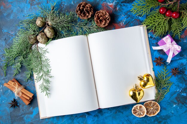 Draufsicht geöffnet Notebook Tannenzweige Kegel Weihnachtsbaum Spielzeug auf blauer Oberfläche