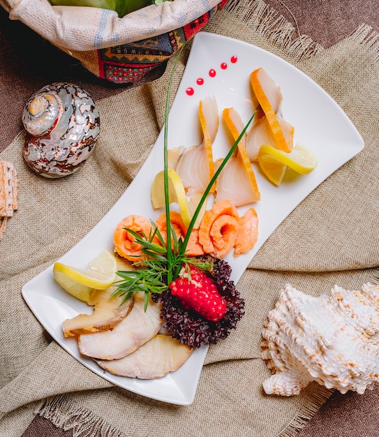 Draufsicht geräucherter Fischplatte Balyk Lachs mit Kräutern Granatapfel und Zitronenscheiben