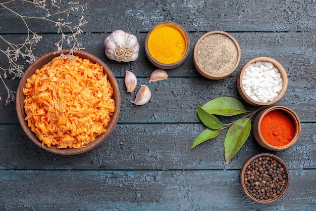 Draufsicht geriebener Karottensalat mit Knoblauch und Gewürzen auf dem dunkelblauen rustikalen Schreibtisch Gesundheit Farbsalat Gemüsediät reif