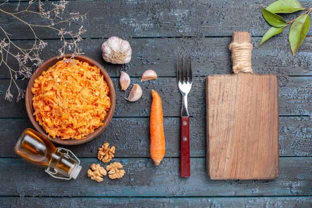 Draufsicht geriebener Karottensalat mit Knoblauch und Walnüssen auf dem dunkelblauen rustikalen Schreibtisch Gesundheit Salat Gemüse Farbe Diät reif