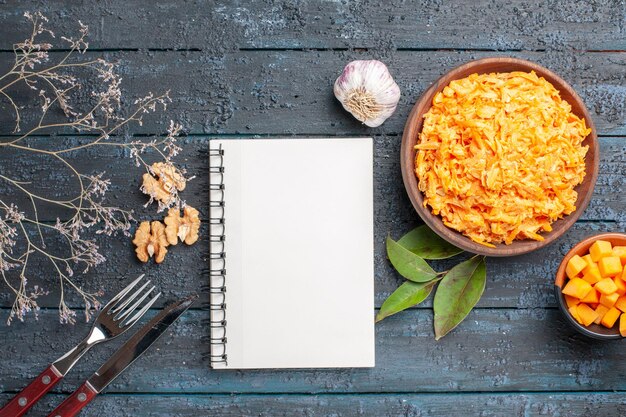 Draufsicht geriebener Karottensalat mit Knoblauch und Walnüssen auf dem dunklen rustikalen Schreibtisch Gesundheit Diätsalat reife orange Farbe