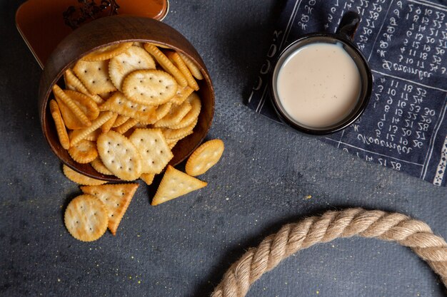 Draufsicht gesalzen verschiedene Cracker mit Tasse Milch auf dem grauen Hintergrundcracker knuspriges Snackfoto