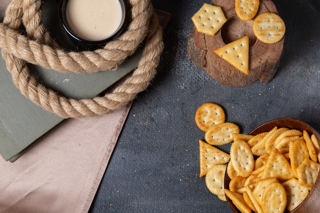 Draufsicht gesalzene leckere Chips mit Tasse Milch auf dem grauen Hintergrundnahrungsmittelfrühstückssnack