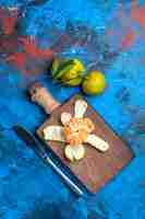Kostenloses Foto draufsicht geschälte mandarine auf schneidebrett abendessen messer frische mandarinen mit blättern auf blauer oberfläche freien platz