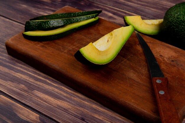 Draufsicht geschnittene Avocado mit Messer auf Schneidebrett auf Holztisch