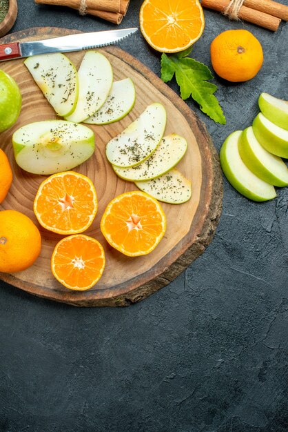 Draufsicht geschnittene Früchte auf Holzbrett auf dunklem Hintergrund