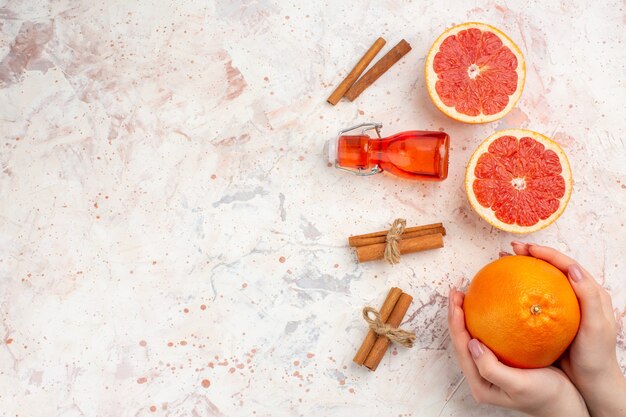 Draufsicht geschnittene Grapefruits Zimtstangen Flasche Grapefruit in weiblicher Hand auf nacktem Oberflächenfreiraum