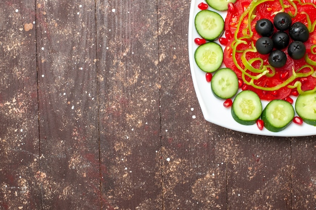 Draufsicht geschnittene Gurken mit Oliven innerhalb Platte auf dem braunen rustikalen Schreibtisch Diät Salat Gemüse Gemüse Vitamin Gesundheit