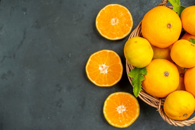 Draufsicht geschnittene Orangen Mandarinen und Orangen im Weidenkorb auf dunklem Hintergrund