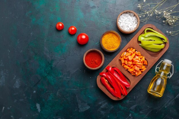 Draufsicht geschnittene Paprika mit Gewürzen und Öl auf dem dunkelblauen Hintergrund