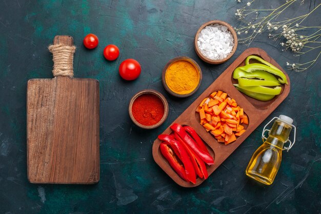 Draufsicht geschnittene Paprika mit Gewürzen und Olivenöl auf dunkelblauem Hintergrund