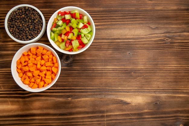 Draufsicht geschnittene Paprika mit verschiedenen Gewürzen auf dem braunen Holztisch Gemüsemehl Lebensmittelgesundheitssalat