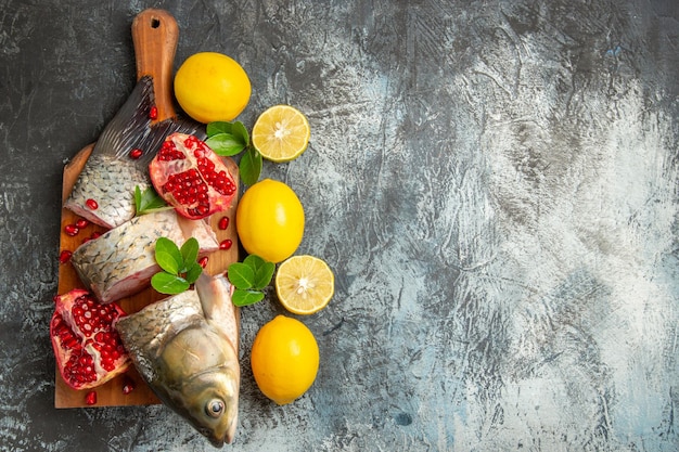 Kostenloses Foto draufsicht geschnittener frischer fisch mit granatäpfeln und zitrone auf heller oberfläche