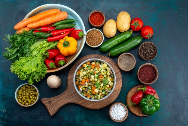 Draufsicht geschnittener Gemüsesalat gepfeffert mit Hühnerscheiben innerhalb Platte mit frischem Gemüse auf dem blauen Schreibtisch Snack Mittagssalat Gemüselebensmittel