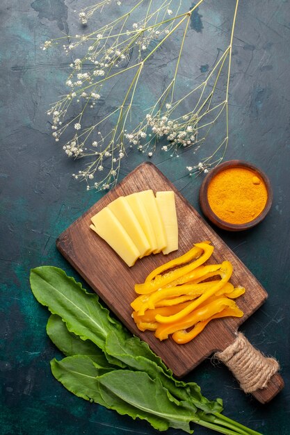 Draufsicht geschnittener Käse mit geschnittenem gelbem Paprika auf dunkelblauem Schreibtisch