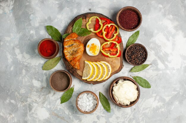 Draufsicht geschnittener Paprika mit Gewürzen und Zitronenscheiben auf hellweißem Schreibtisch