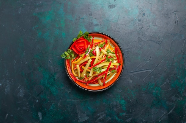 Draufsicht geschnittener Paprika verschiedenfarbiger Gemüsesalat innerhalb Platte auf dem dunkelblauen Hintergrund