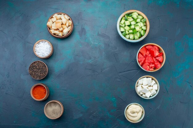 Draufsicht geschnittenes frisches Gemüse mit Salzgewürzsaucen auf dem dunklen Schreibtisch Essen Mahlzeit Gewürzküche