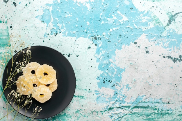 Draufsicht getrocknete Ananasringe in der Platte auf hellblauem Hintergrundfrüchten Ananas trockener süßer Zucker