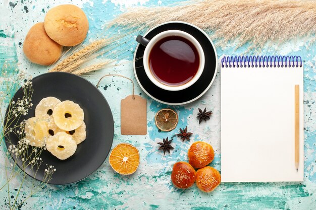 Draufsicht getrocknete Ananasringe mit Tasse Tee und Keksen auf blauem Hintergrundkuchen backen Fruchtkeks süßer Zuckerkeks